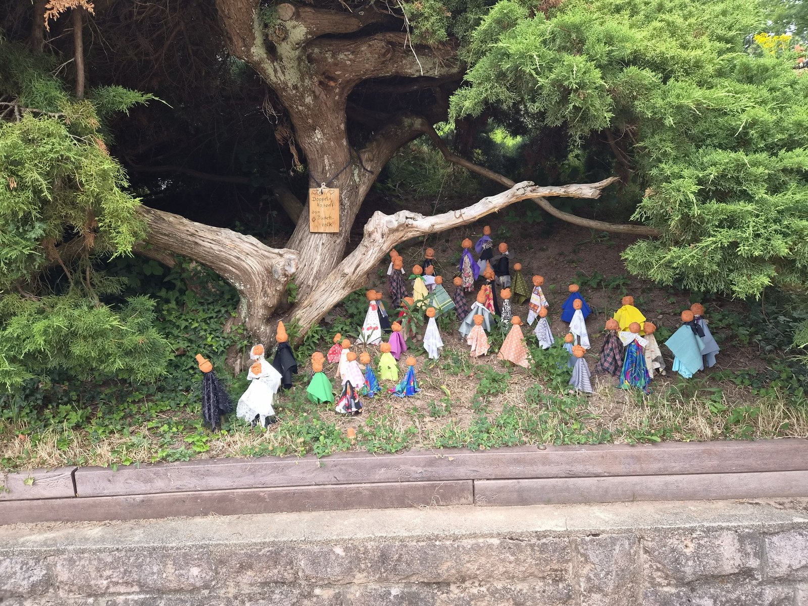 Bemalte Tonfiguren als Hochzeitszug des Buschvolks unter einem Baum im Schulgarten