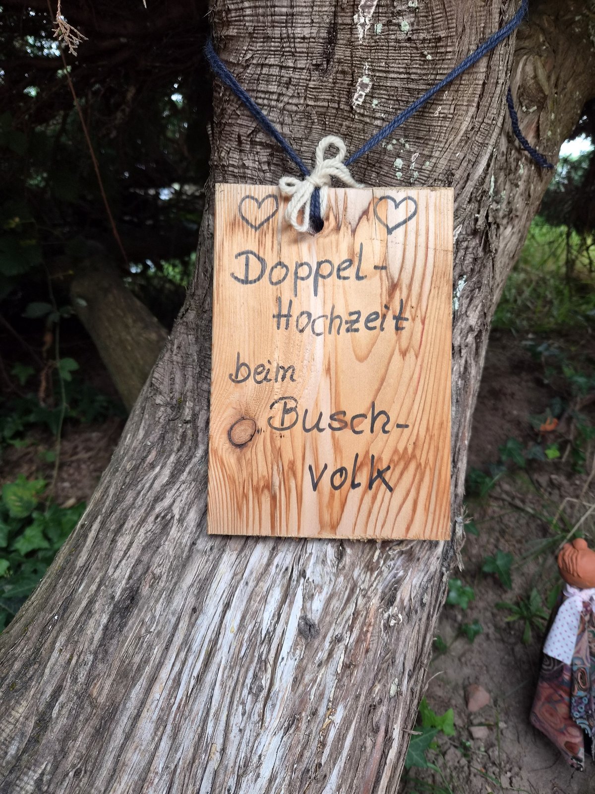 Selbstgeschriebenes Holzschild: Doppel-Hochzeit beim Buschvolk