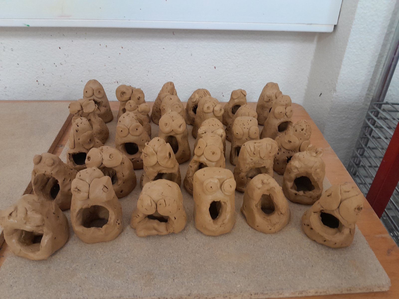 Getöpferte Erdbeermonster aus Ton, aufgereiht auf einem Tisch